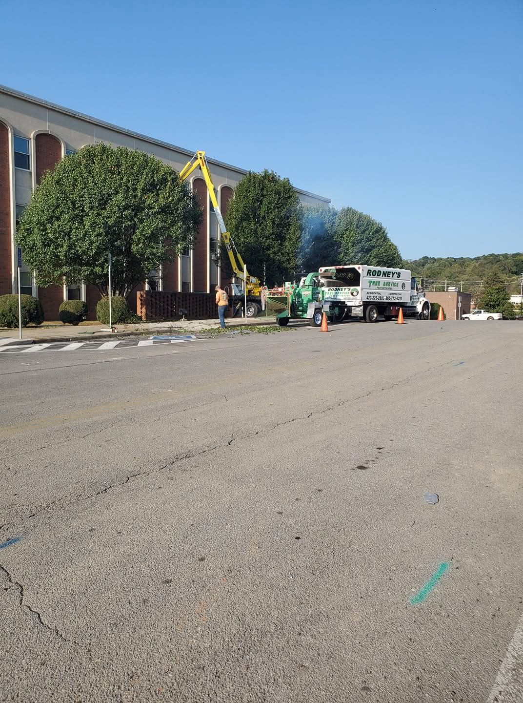Lift and chip truck working a tree line outside an office building