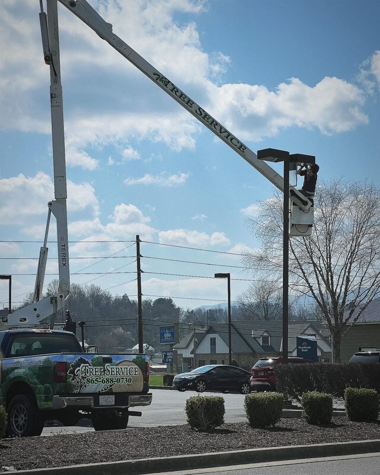 Boom lift reaching a car park light pole for overhead clearance
