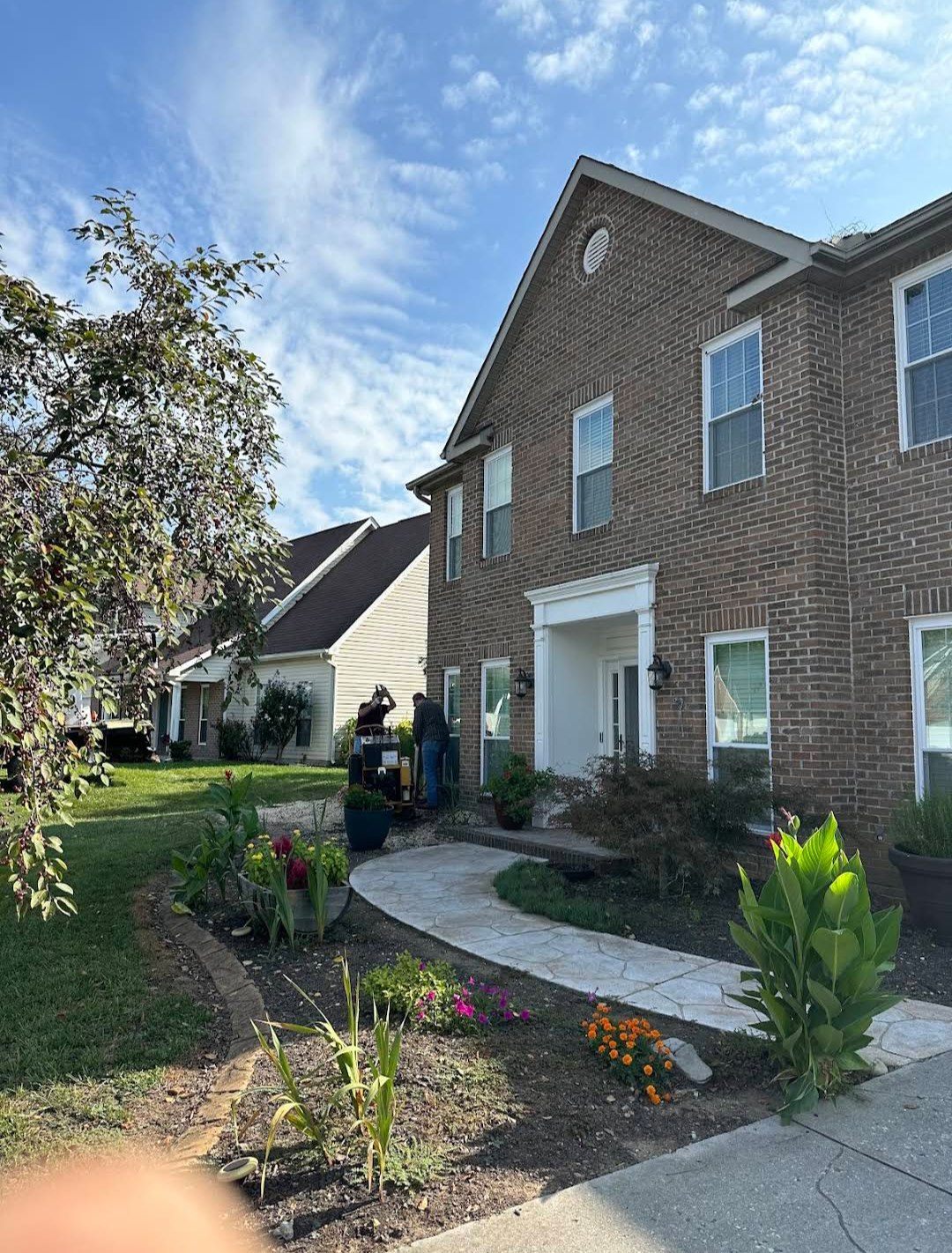 Crew working the front of a two-storey brick home